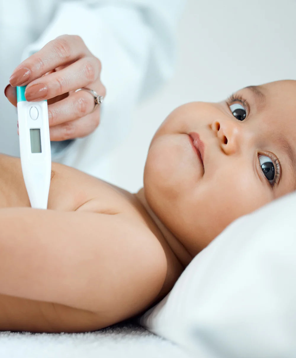 Un niño al que le están tomando la fiebre con un termómetro.
